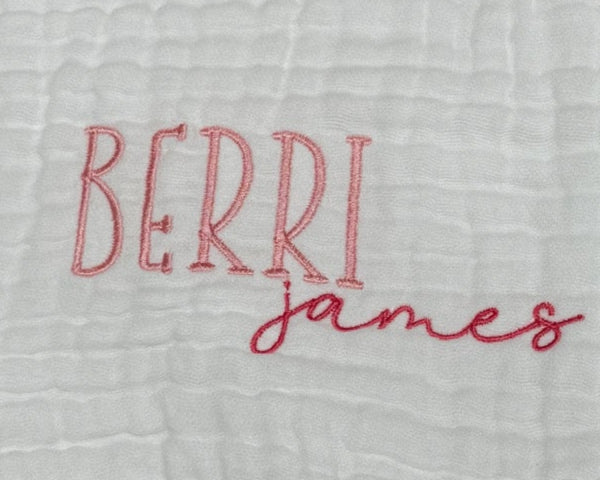 Personalized white baby burp cloth with embroidered first and middle names — "Berri" in pink block letters and "james" in darker pink script font. Custom baby gift on soft muslin fabric, perfect for newborns, baby showers, and keepsakes.