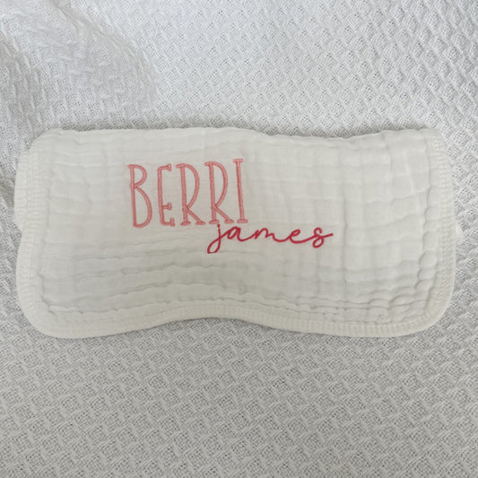 Personalized white baby burp cloth with embroidered first and middle names — "Berri" in pink block letters and "james" in darker pink script font. Custom baby gift on soft muslin fabric, perfect for newborns, baby showers, and keepsakes.
