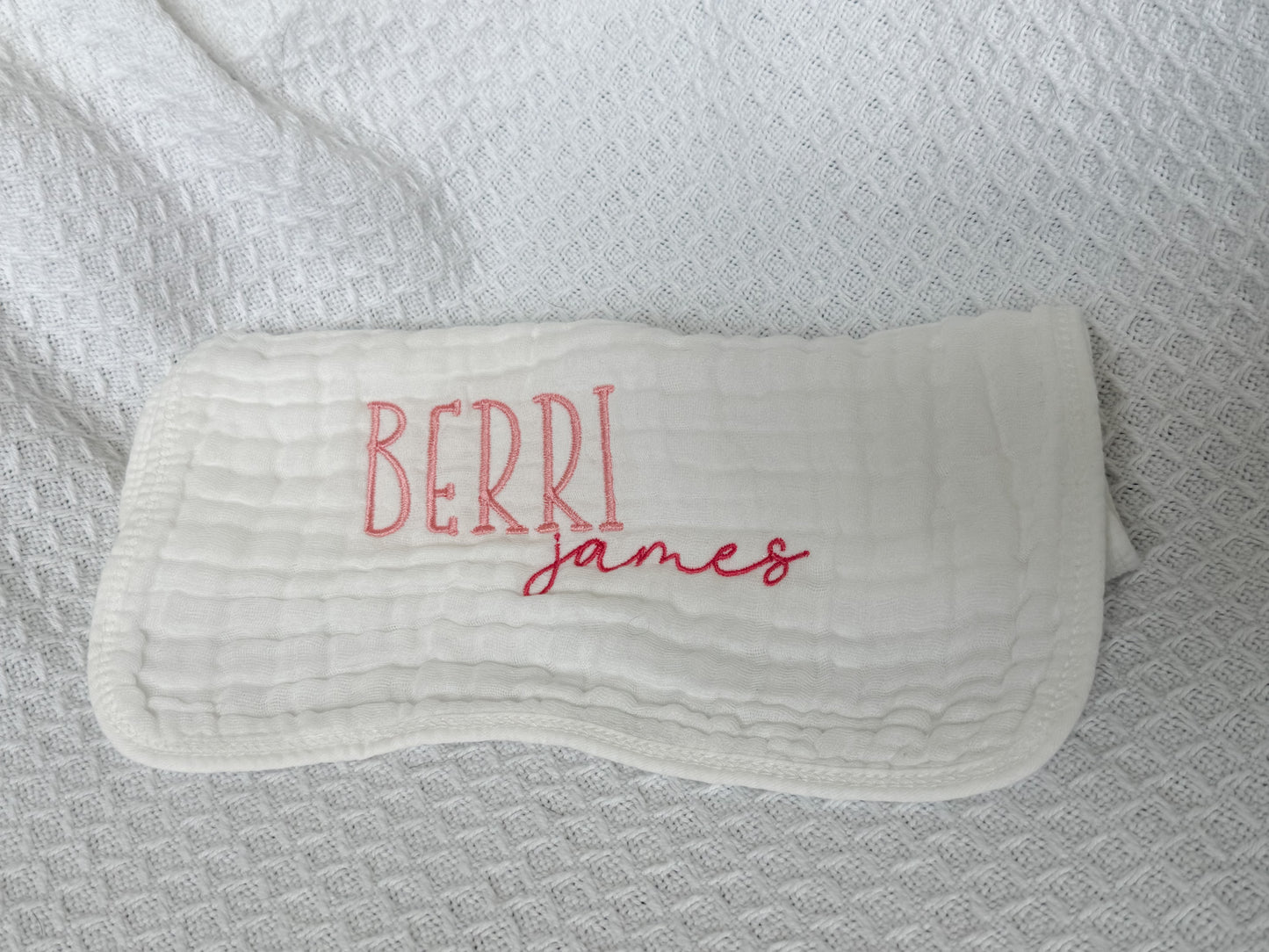 Personalized white baby burp cloth with embroidered first and middle names — "Berri" in pink block letters and "james" in darker pink script font. Custom baby gift on soft muslin fabric, perfect for newborns, baby showers, and keepsakes.