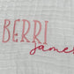 Personalized white baby burp cloth with embroidered first and middle names — "Berri" in pink block letters and "james" in darker pink script font. Custom baby gift on soft muslin fabric, perfect for newborns, baby showers, and keepsakes.